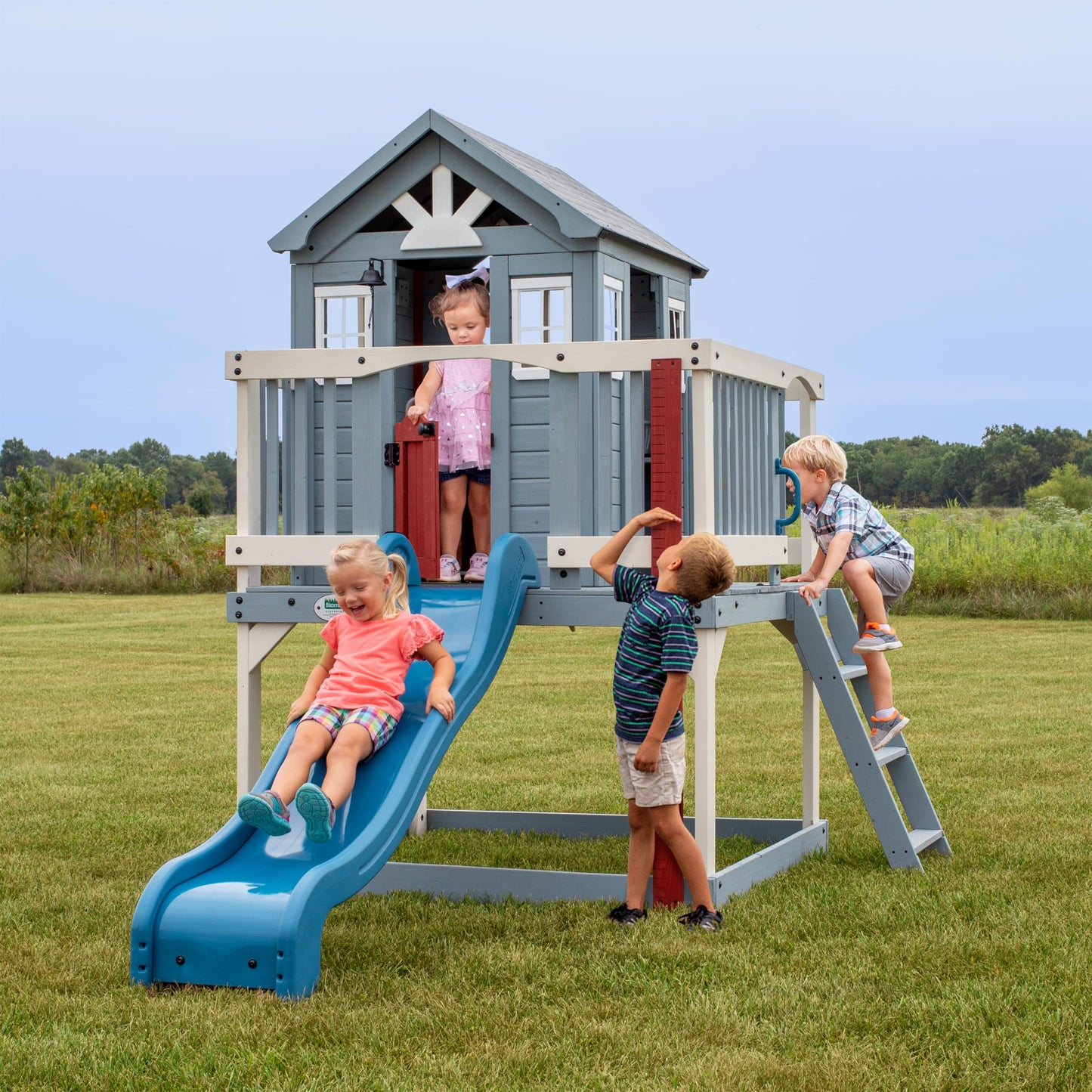 Backyard Discovery Beacon Heights Elevated Cedar Wooden Kids Playhouse with Wave Slide, Play Kitchen, Wrap-Around Deck, Flat-Step Ladder, Half Door, Windows, Bell, and Growth Chart for Outdoor Play